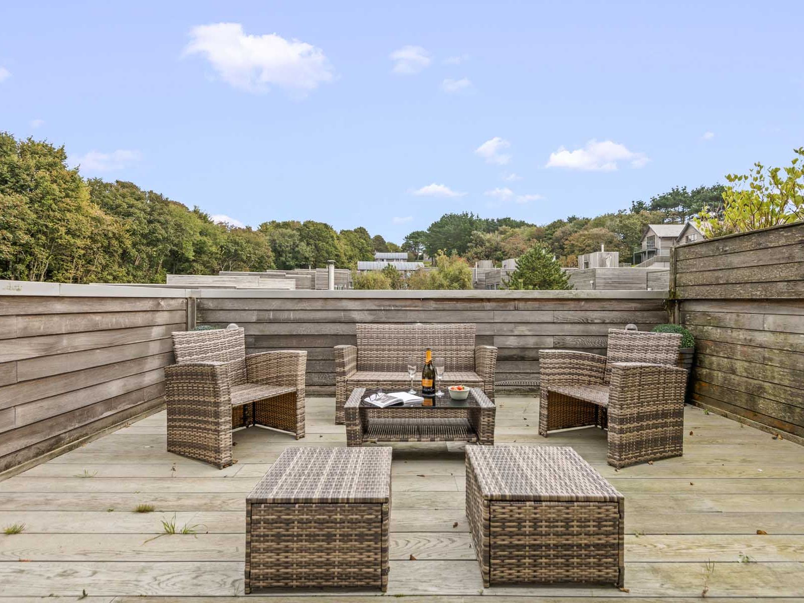 Outdoor rooftop patio with wicker furniture and surrounding wooden fencing