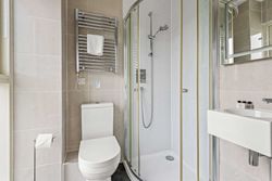 Modern bathroom with toilet, glass shower enclosure, towel rack, and sink