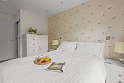 Cozy bedroom with white furniture, seagull wallpaper, and breakfast tray on the bed
