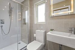 Modern bathroom with glass shower, toilet, sink, and illuminated mirror