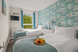 Twin bedroom with nautical wallpaper, breakfast tray, and window with blue curtains