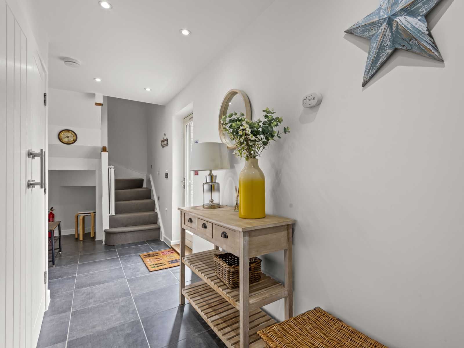 Modern hallway with wooden console table, stairs, and decorative items
