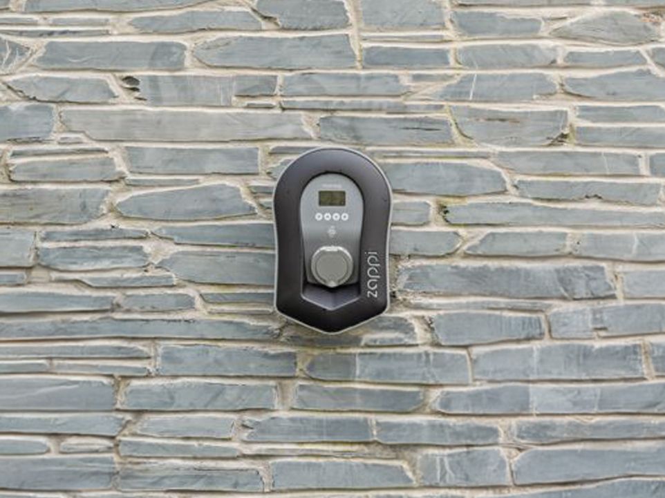 Electric vehicle charger mounted on a stone wall