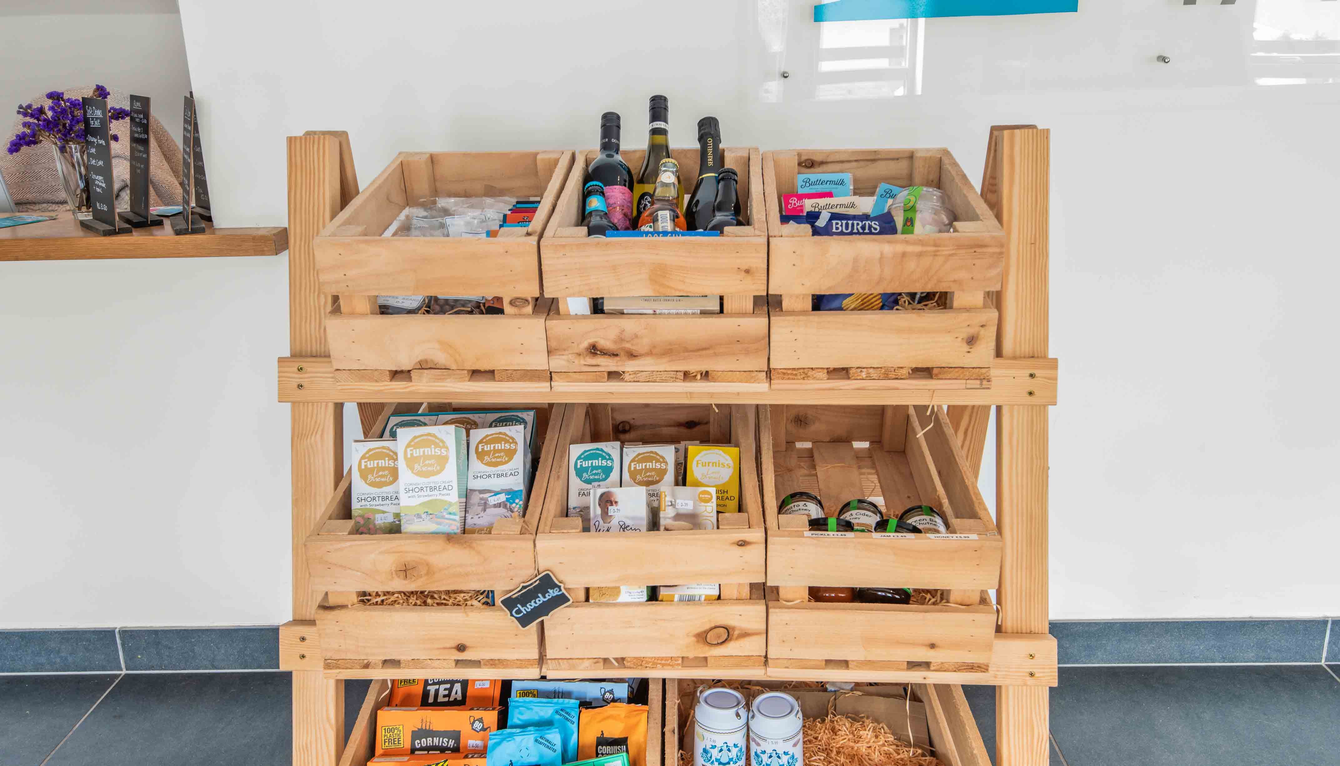 Wooden display rack with assorted local snacks, drinks, and packaged goods