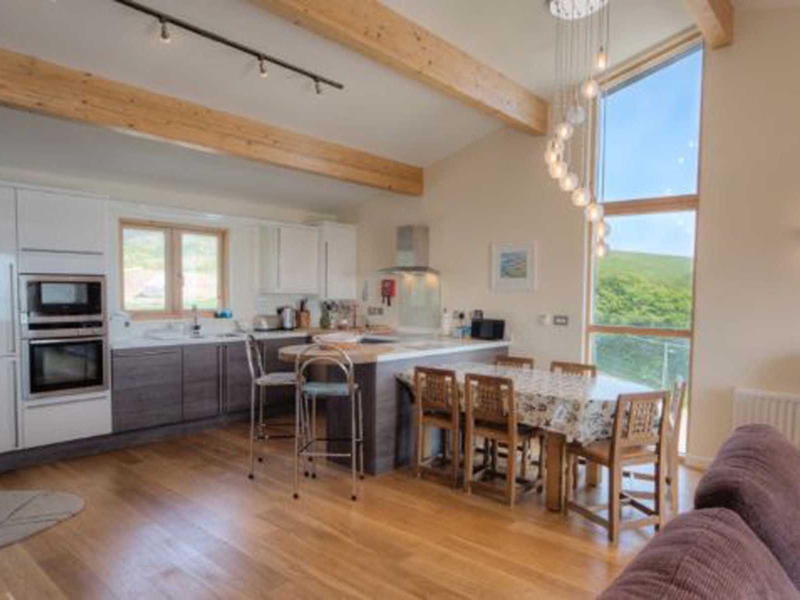 Modern open-plan kitchen and dining area with wooden beams and large windows