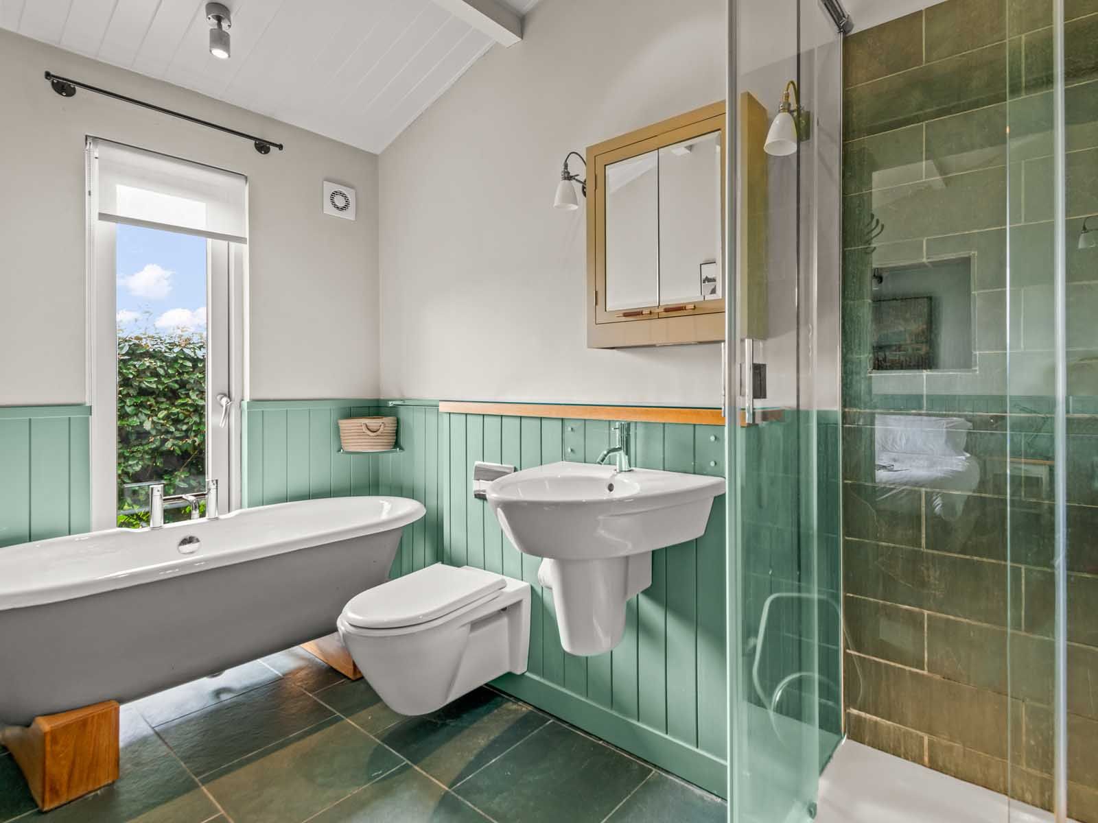 Modern bathroom with freestanding tub, glass shower, and green paneling
