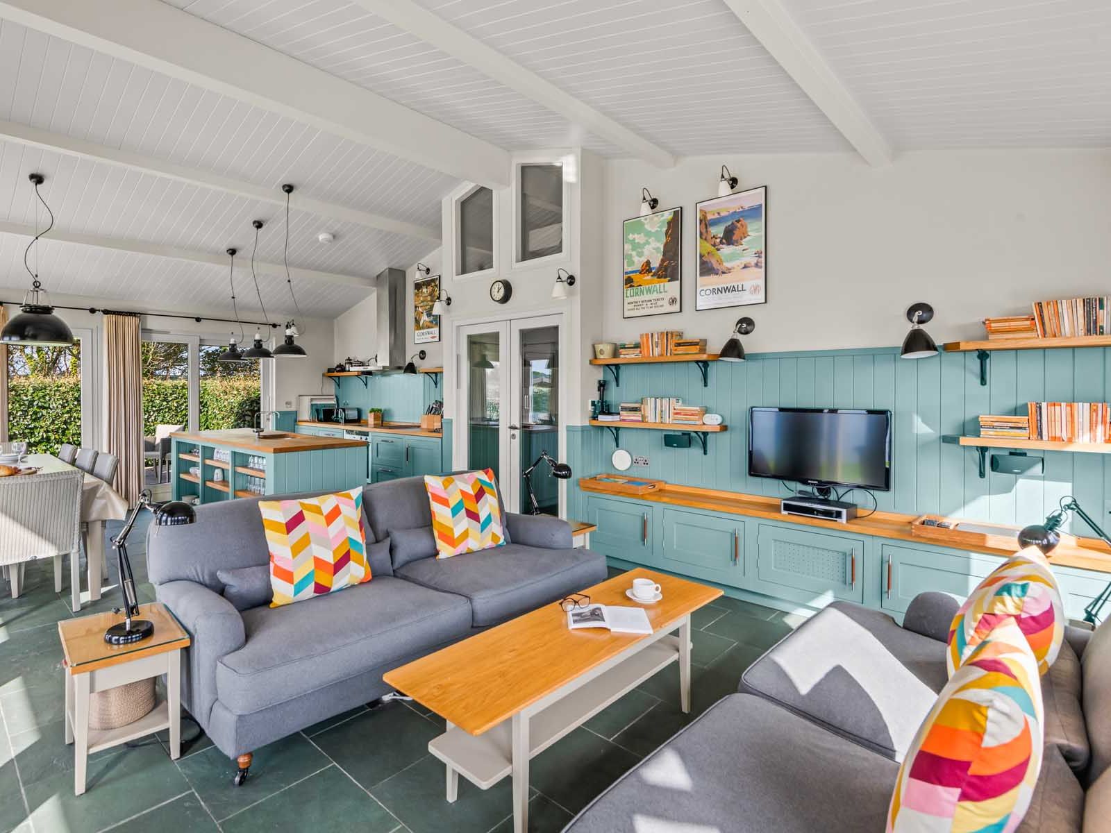 Bright open-plan living area with cozy seating, dining table, and modern kitchen.