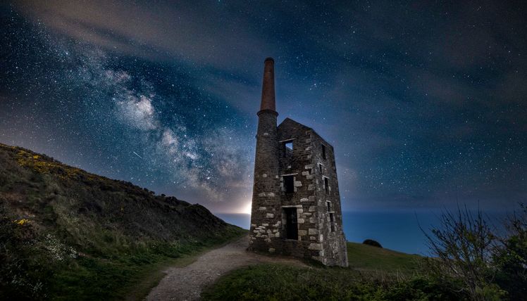 Old stone building with a chimney under a starry night sky and Milky Way.