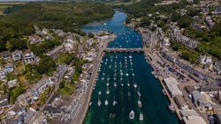 Aerial view of a coastal town with boats docked in a harbor and a bridge crossing the river.
