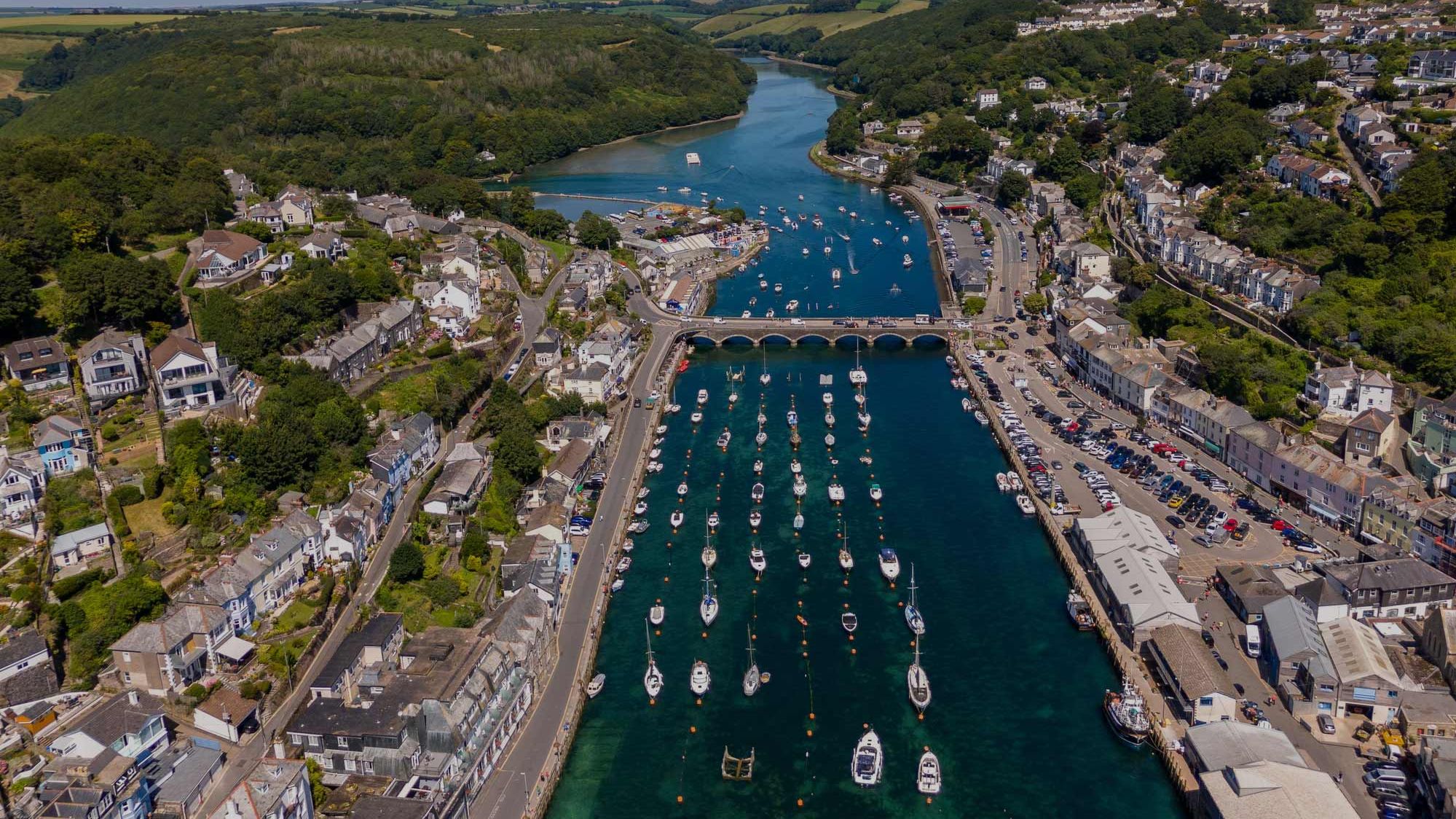 Aerial view of a coastal town with boats docked in a harbor and a bridge crossing the river.