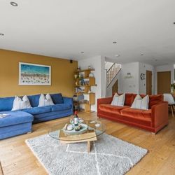Modern open-plan living room with colorful sofas, wooden flooring, and contemporary decor.