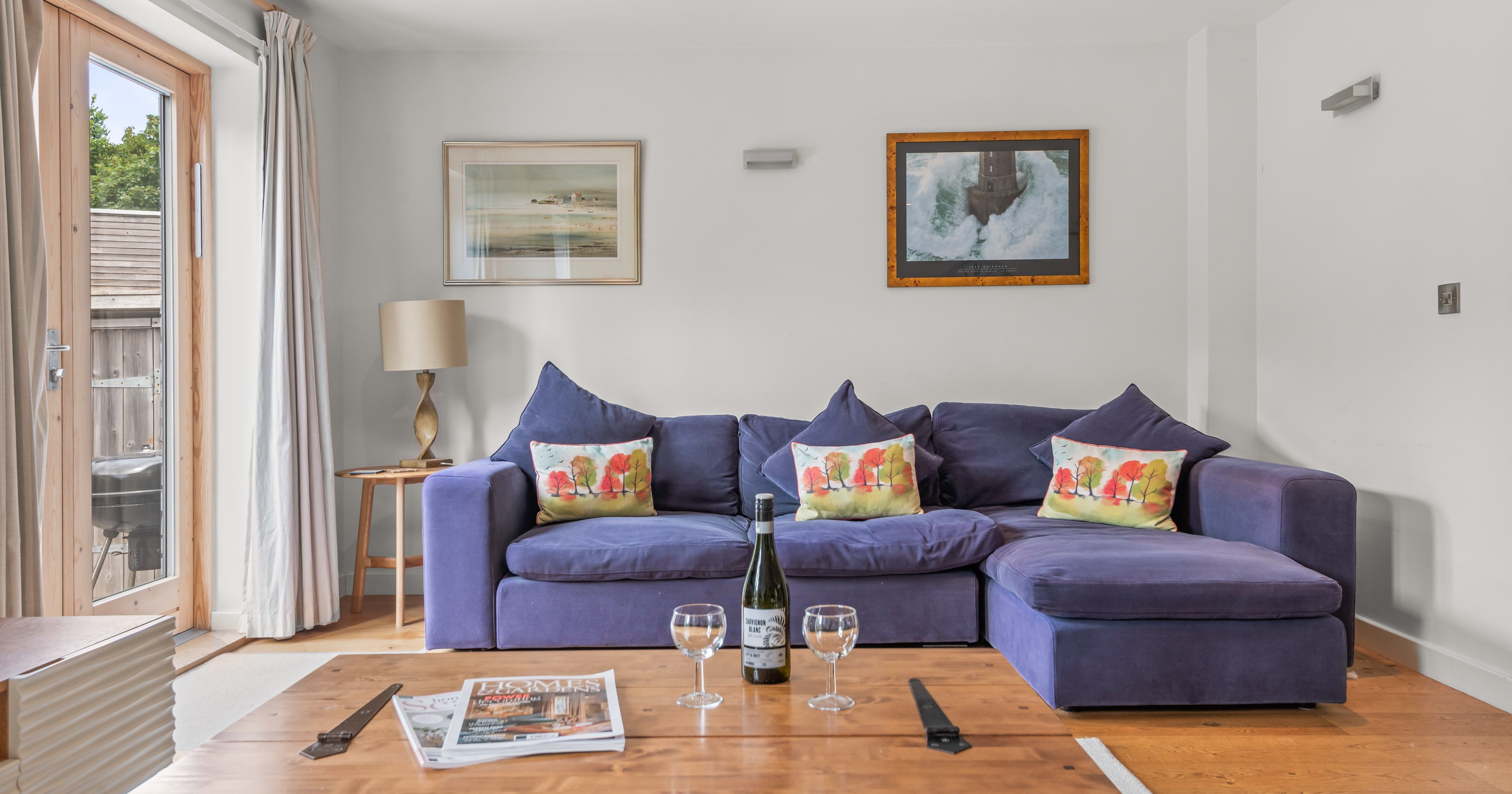 Cozy living room with a blue sectional sofa, decorative pillows, wooden coffee table, and wall art.