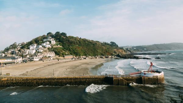 Coastal town with sandy bay and harbour breakwater under a blue sky