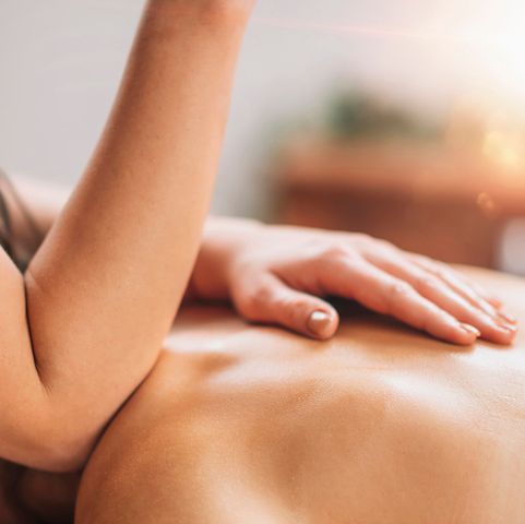 Close-up of a person receiving a back massage with a therapist’s forearm and hand applying pressure