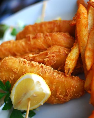 Battered fish fillets with chips, lemon wedge and parsley on a plate