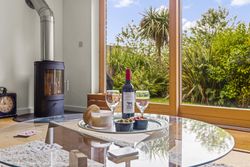 Wine and glasses on a table in front of a window with garden view and a wood-burning stove