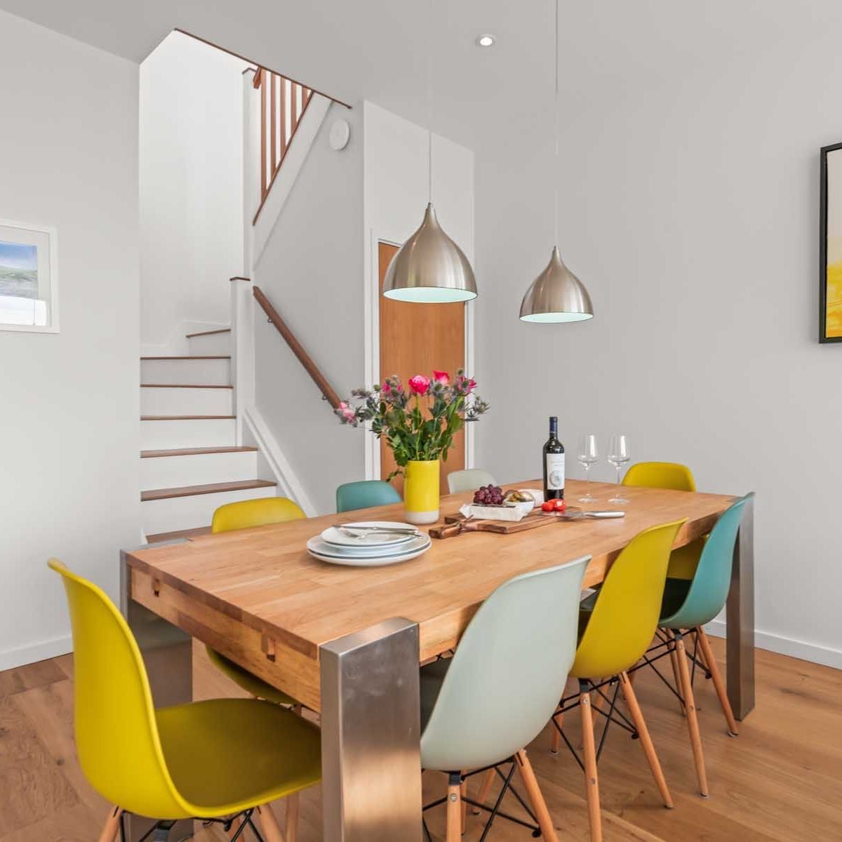 Modern dining room with wooden table, colourful chairs and pendant lights