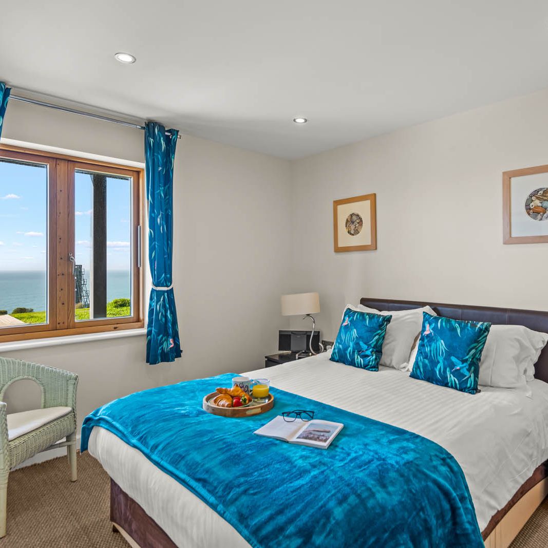 Bright bedroom with blue curtains and sea view through the window