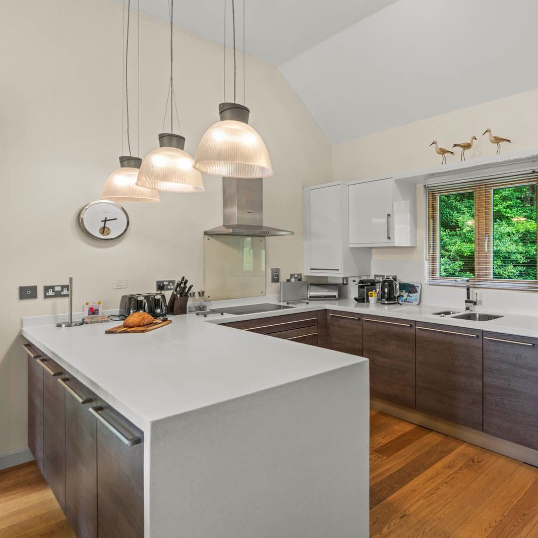 Modern kitchen with white island, dark wood cabinets and pendant lights beside a window