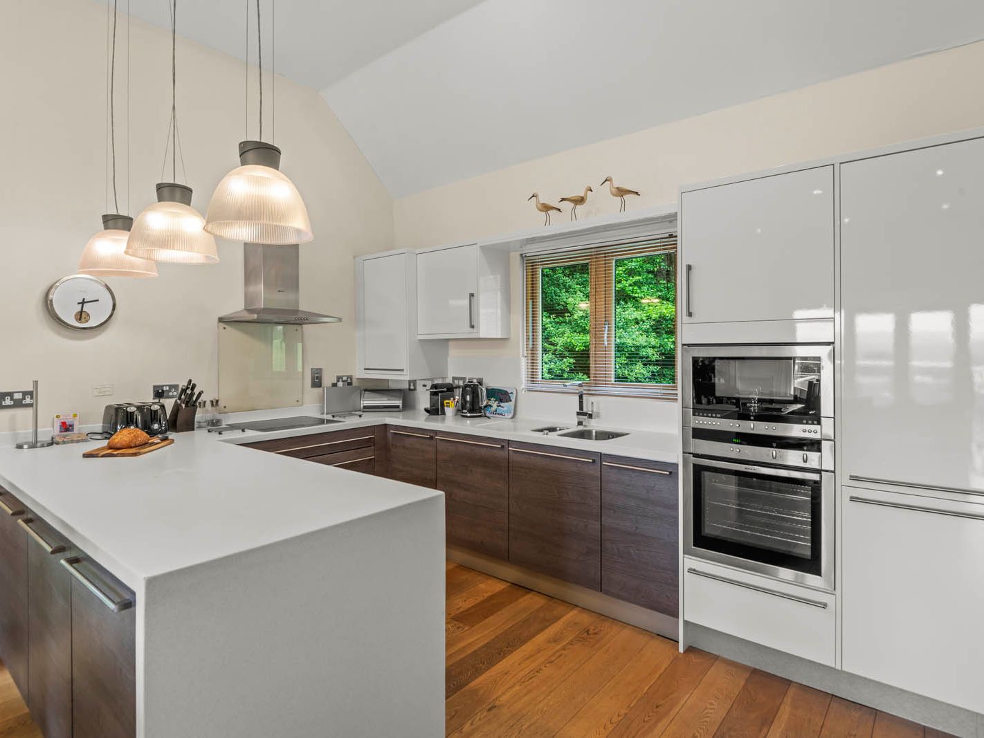 Modern kitchen with white island, dark wood cabinets and pendant lights beside a window