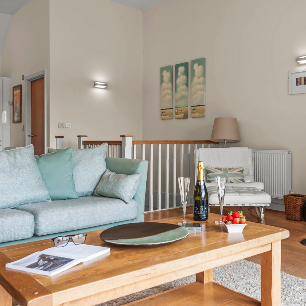 Cosy living room with light blue sofa, wooden coffee table and a lit wood-burning stove
