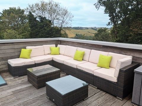Outdoor corner sofa set with cream cushions and lime green pillows on a wooden deck
