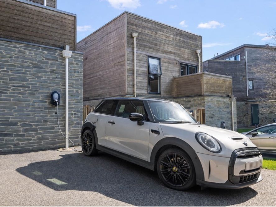 Electric car charging on a driveway outside modern stone and timber-clad flats