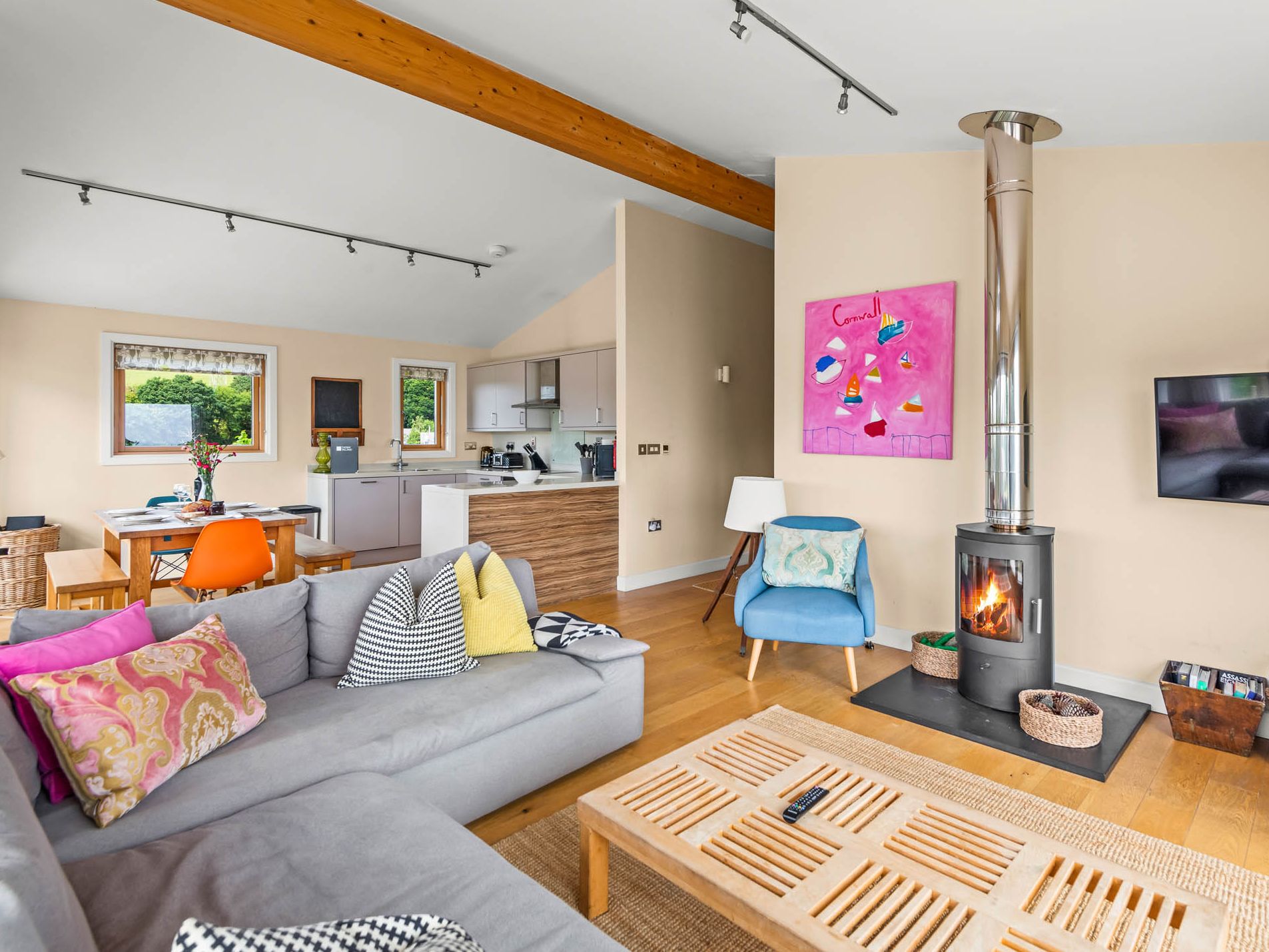 Open-plan living room and kitchen with wood-burning stove, grey sofa and dining table