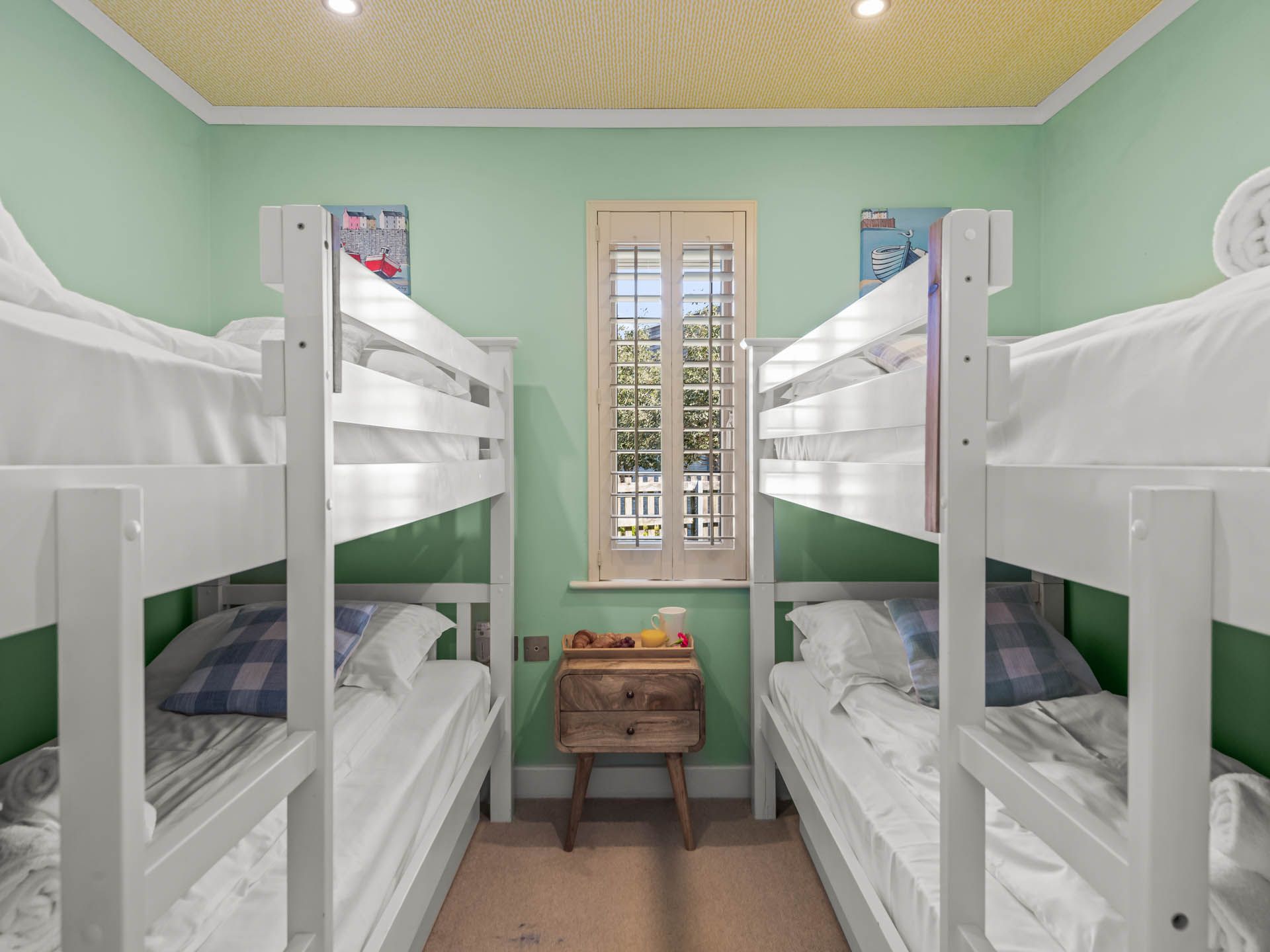 Bright bunk bedroom with two white bunk beds and a window with shutters