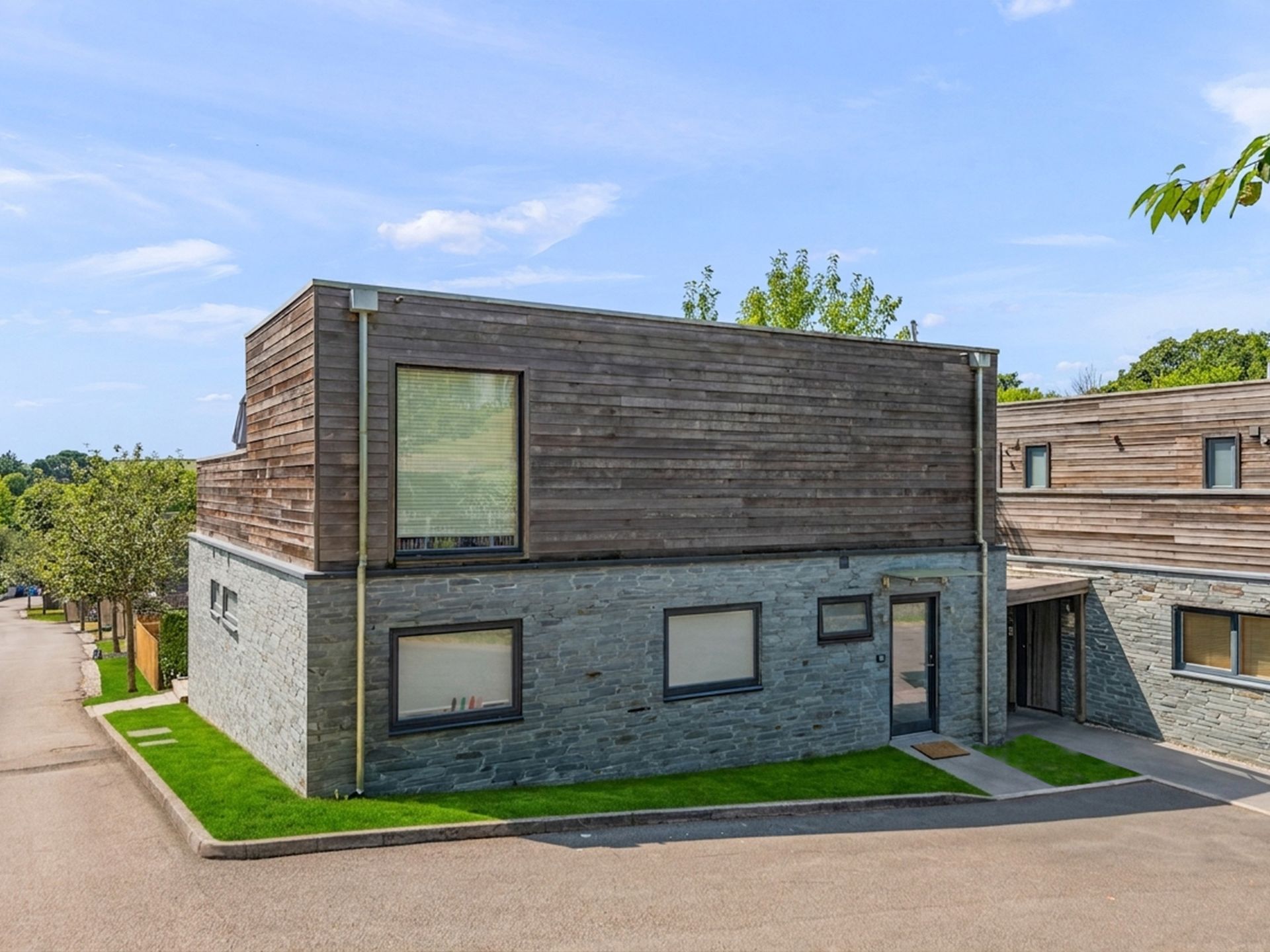 Modern timber-and-stone clad building exterior under a blue sky