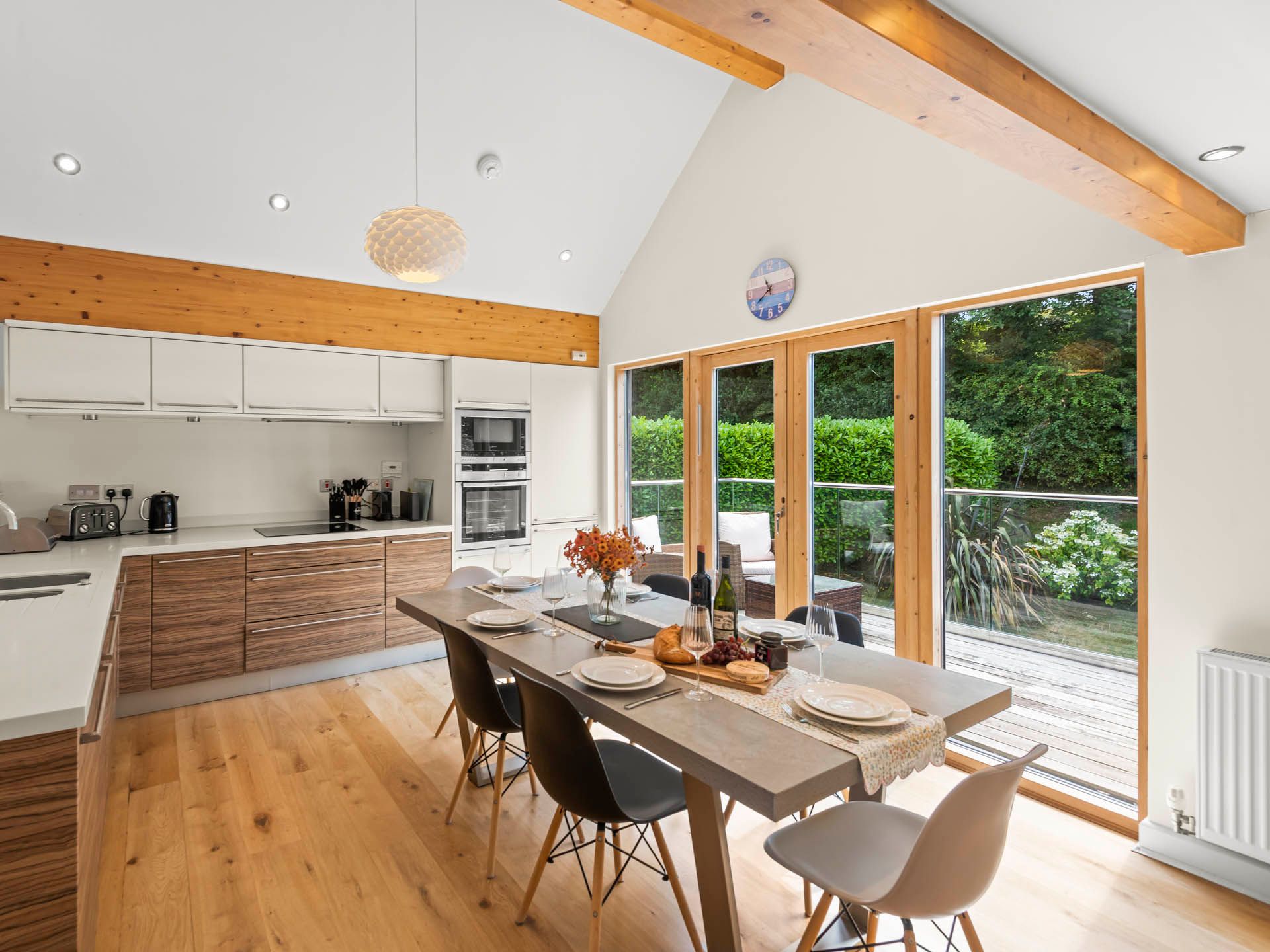 Modern open-plan kitchen and dining area with wooden beams and large glass doors to garden