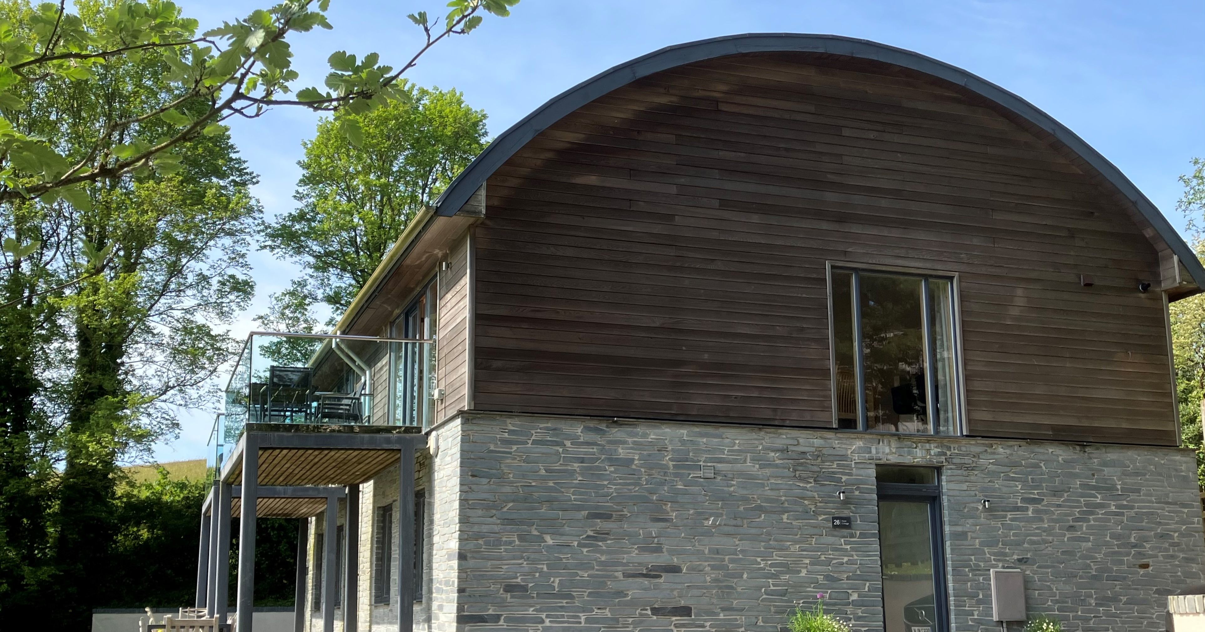 Modern house with stone lower level, wooden upper level, and curved roof