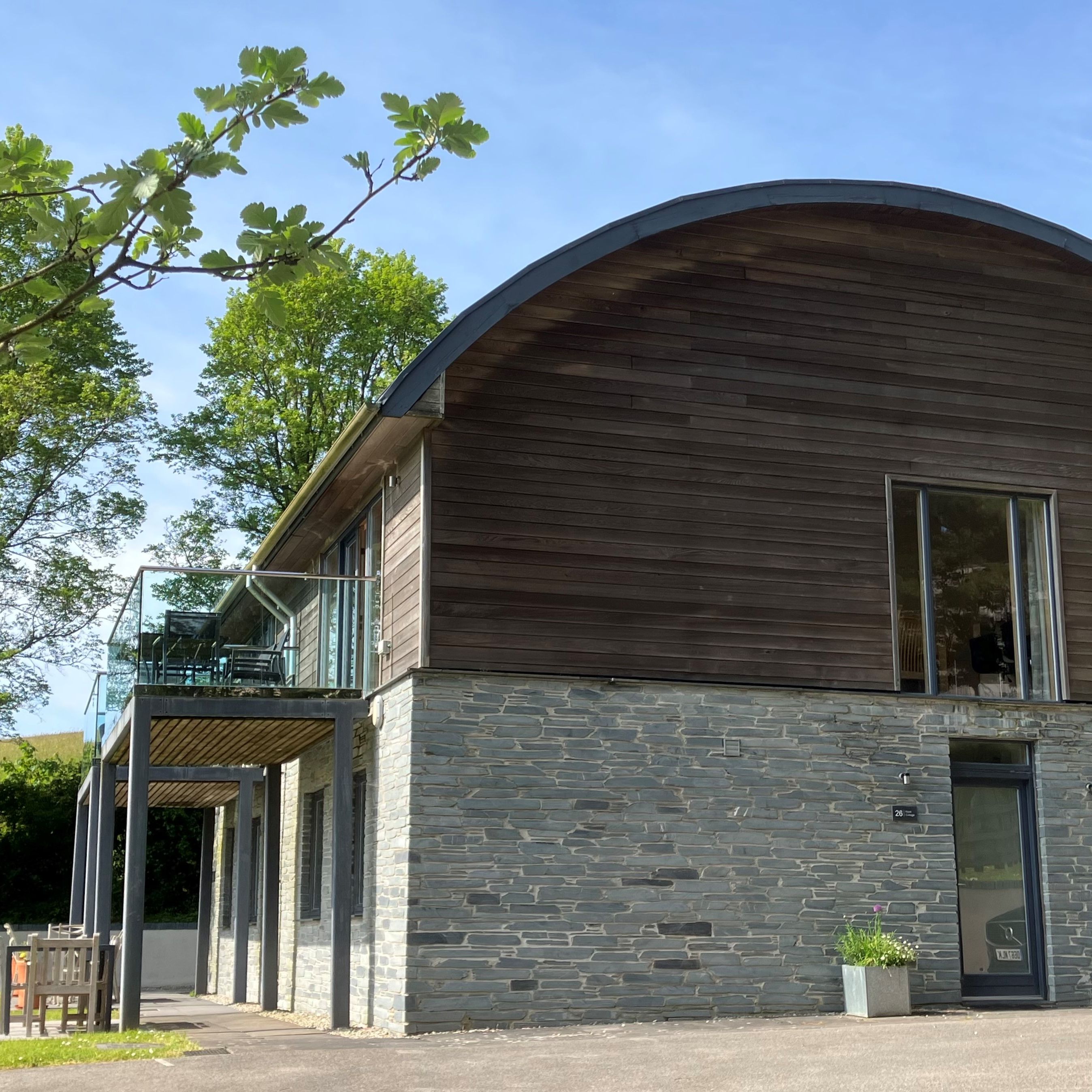 Modern house with stone lower level, wooden upper level, and curved roof