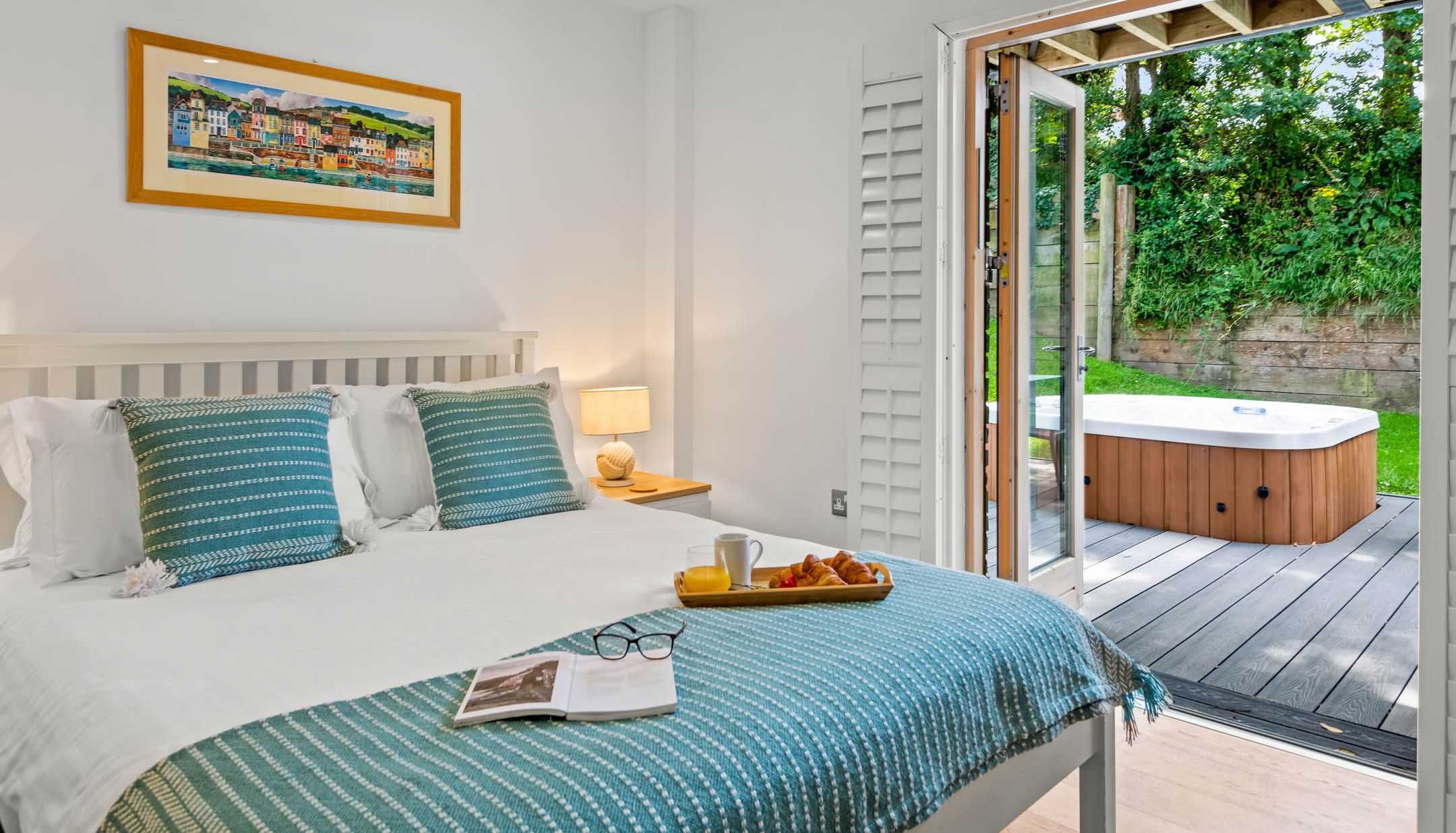 Bright bedroom with double bed and open doors to a patio hot tub