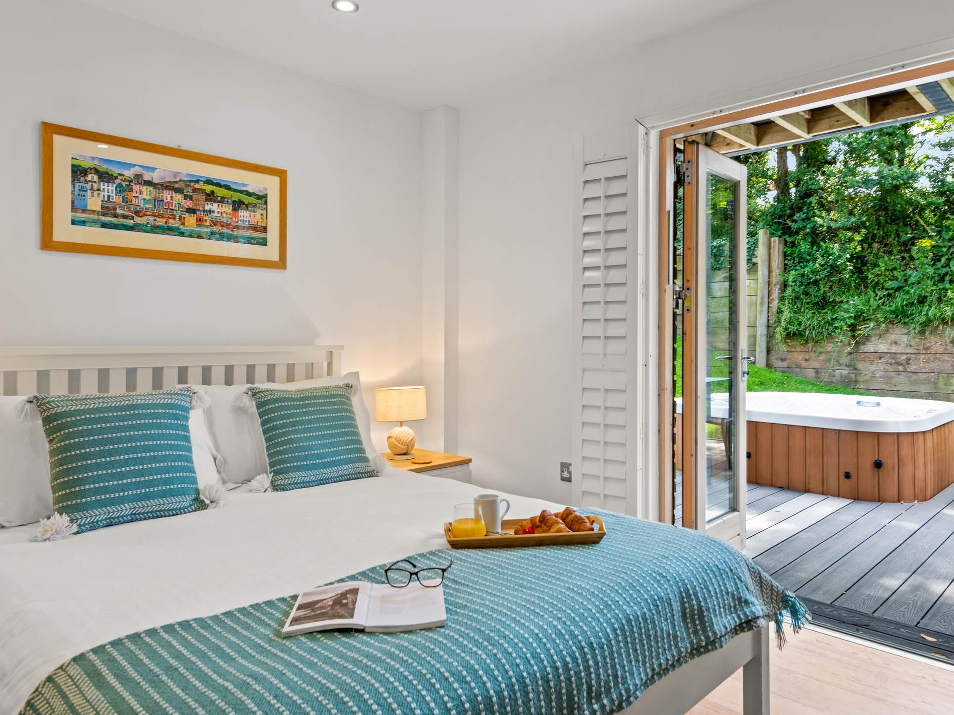 Bright bedroom with double bed and open doors to a patio hot tub