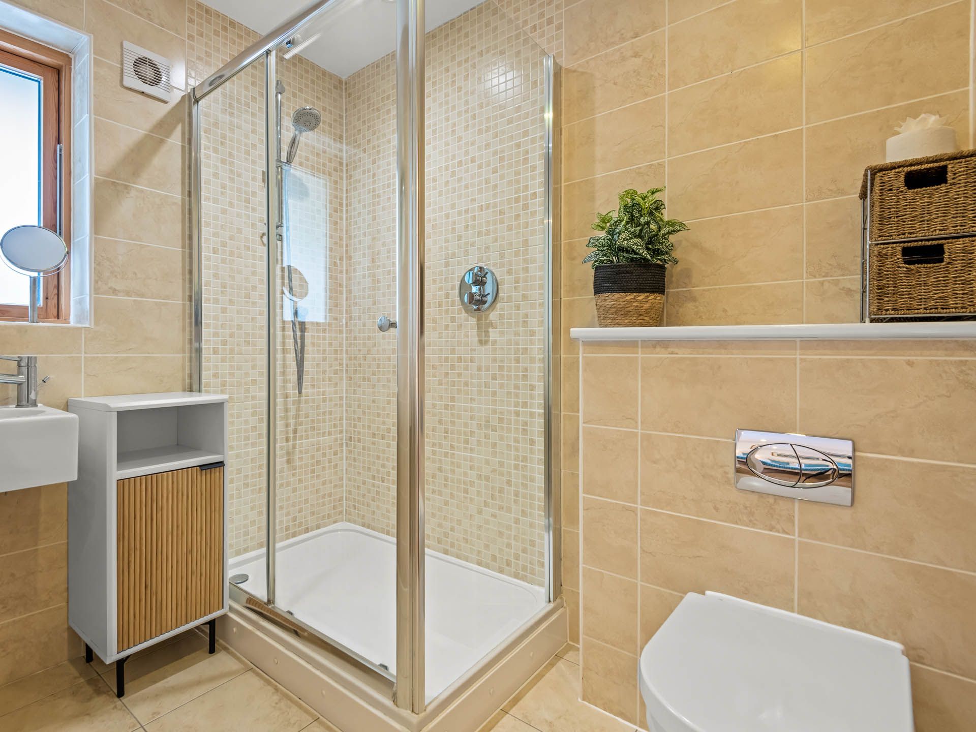 Modern bathroom with glass shower enclosure, beige tiles, wall-mounted basin and toilet