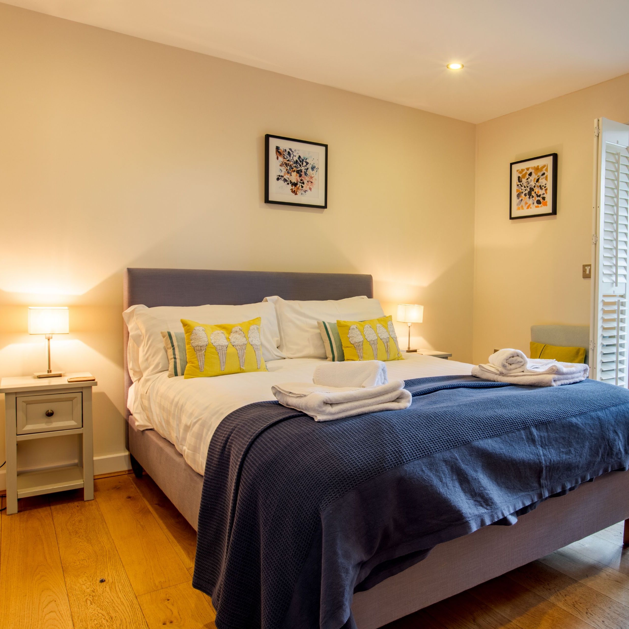 Cosy bedroom with double bed, bedside lamps and open doors to a deck with a hot tub