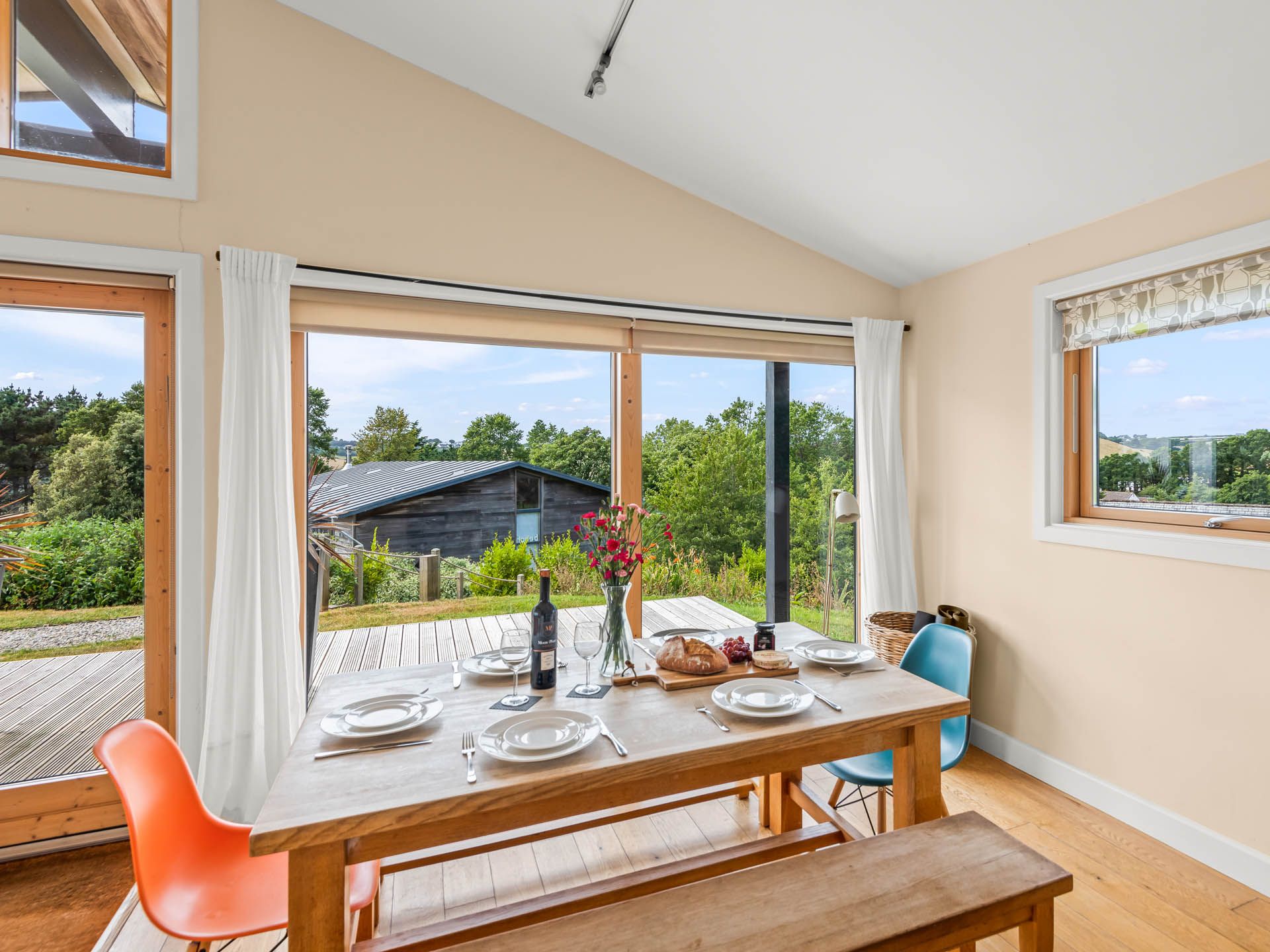 Dining table set for four by large windows with countryside views