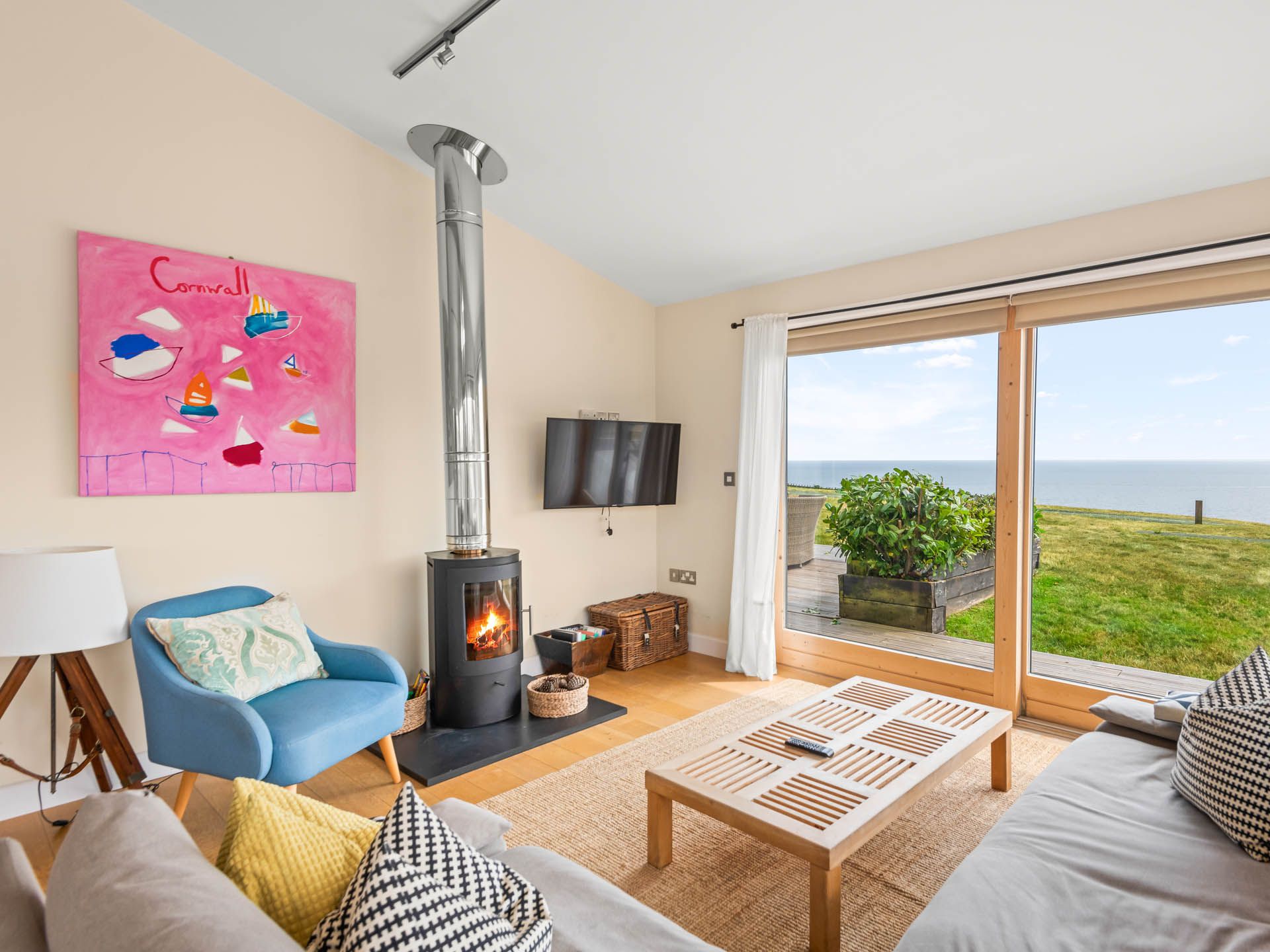 Cosy living room with wood-burning stove and sea view through large sliding doors