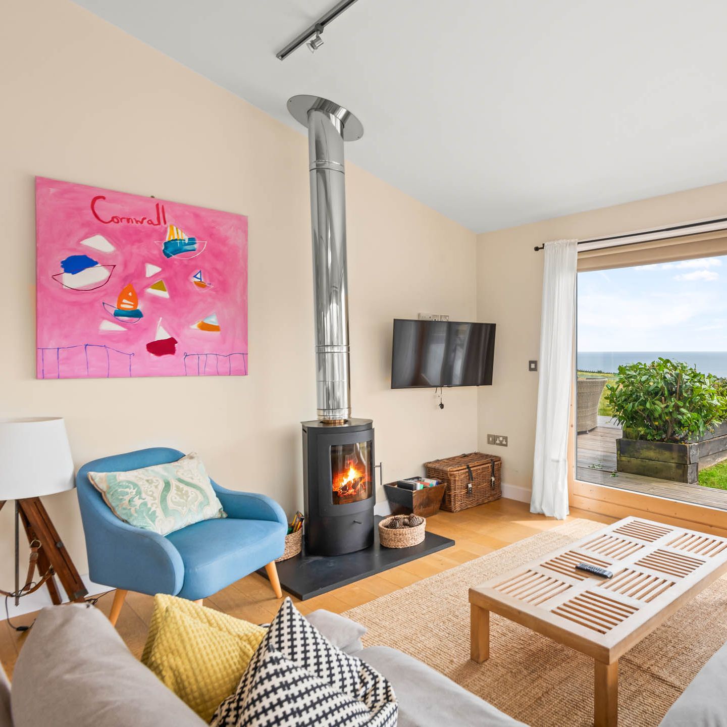 Cosy living room with wood-burning stove and sea view through large sliding doors