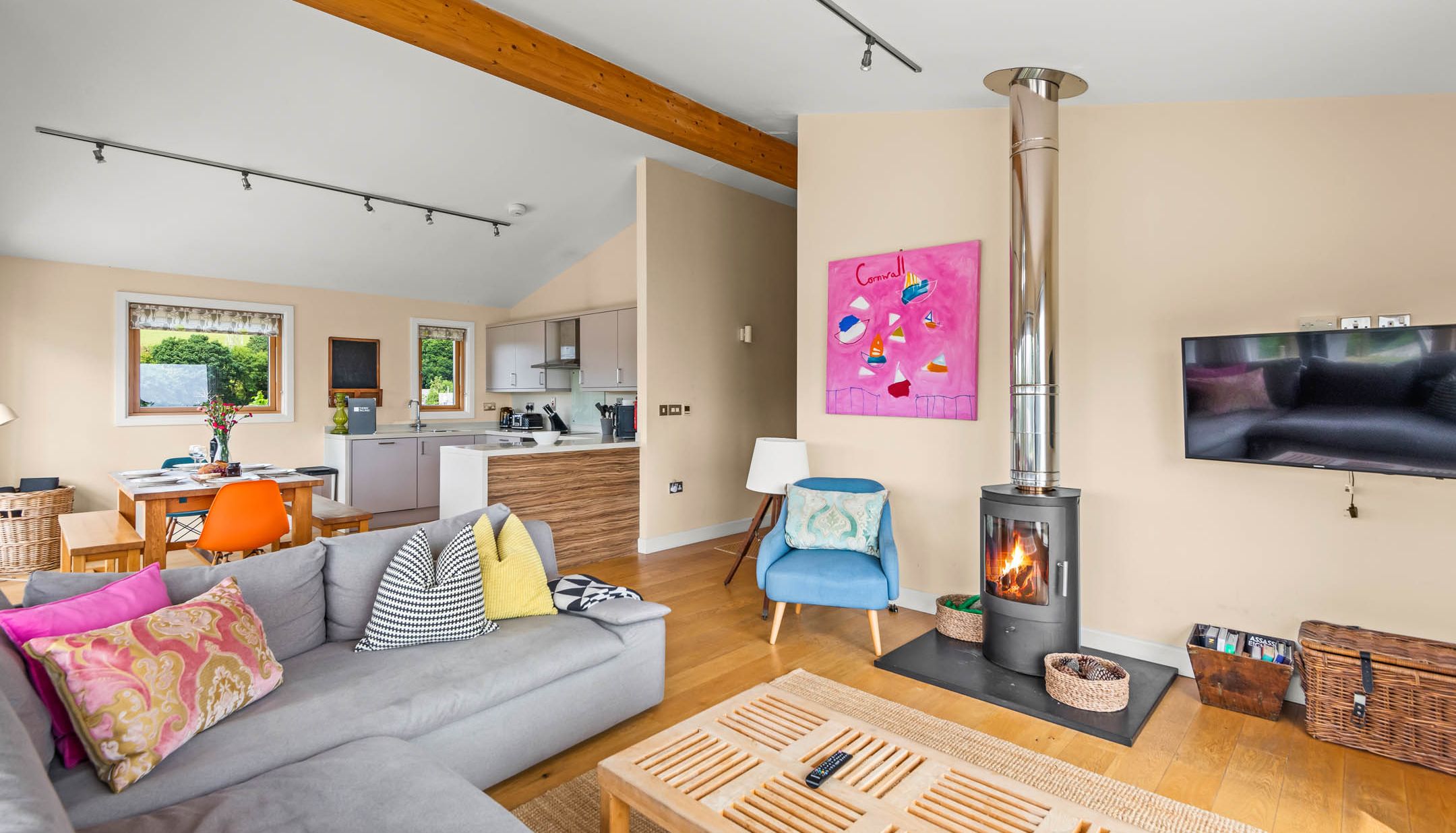 Open-plan living room with wood-burning stove, sofa and dining area leading to a modern kitchen