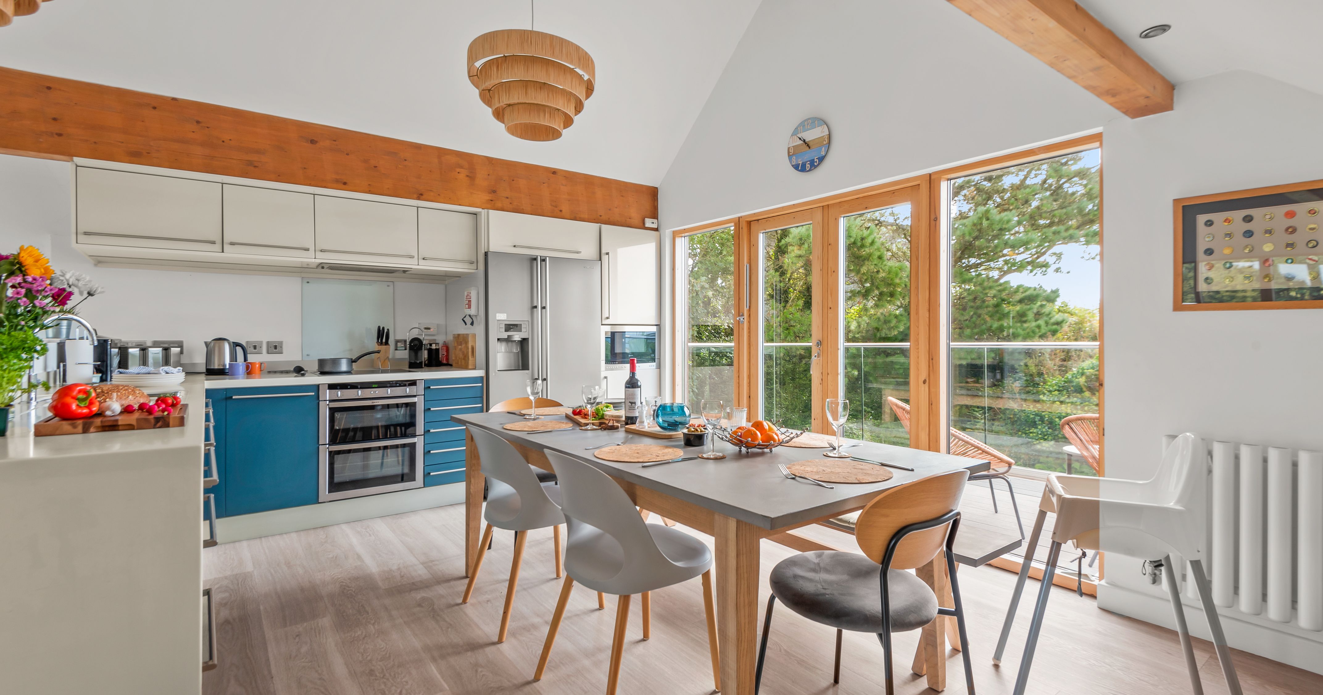 Modern kitchen and dining area with large windows, wooden beams, and a set dining table