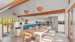 Modern kitchen and dining area with wooden beams, blue cabinets, and large windows.