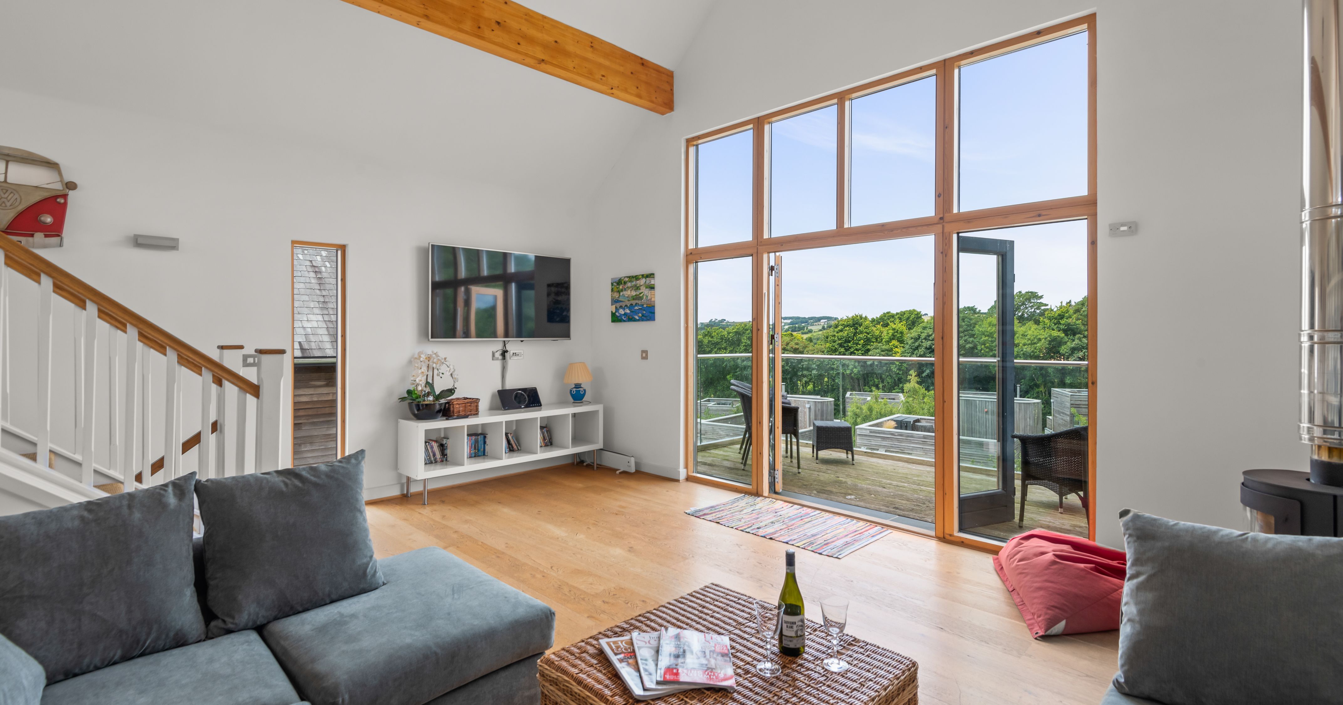 Modern living room with large windows and a view of a deck and green trees