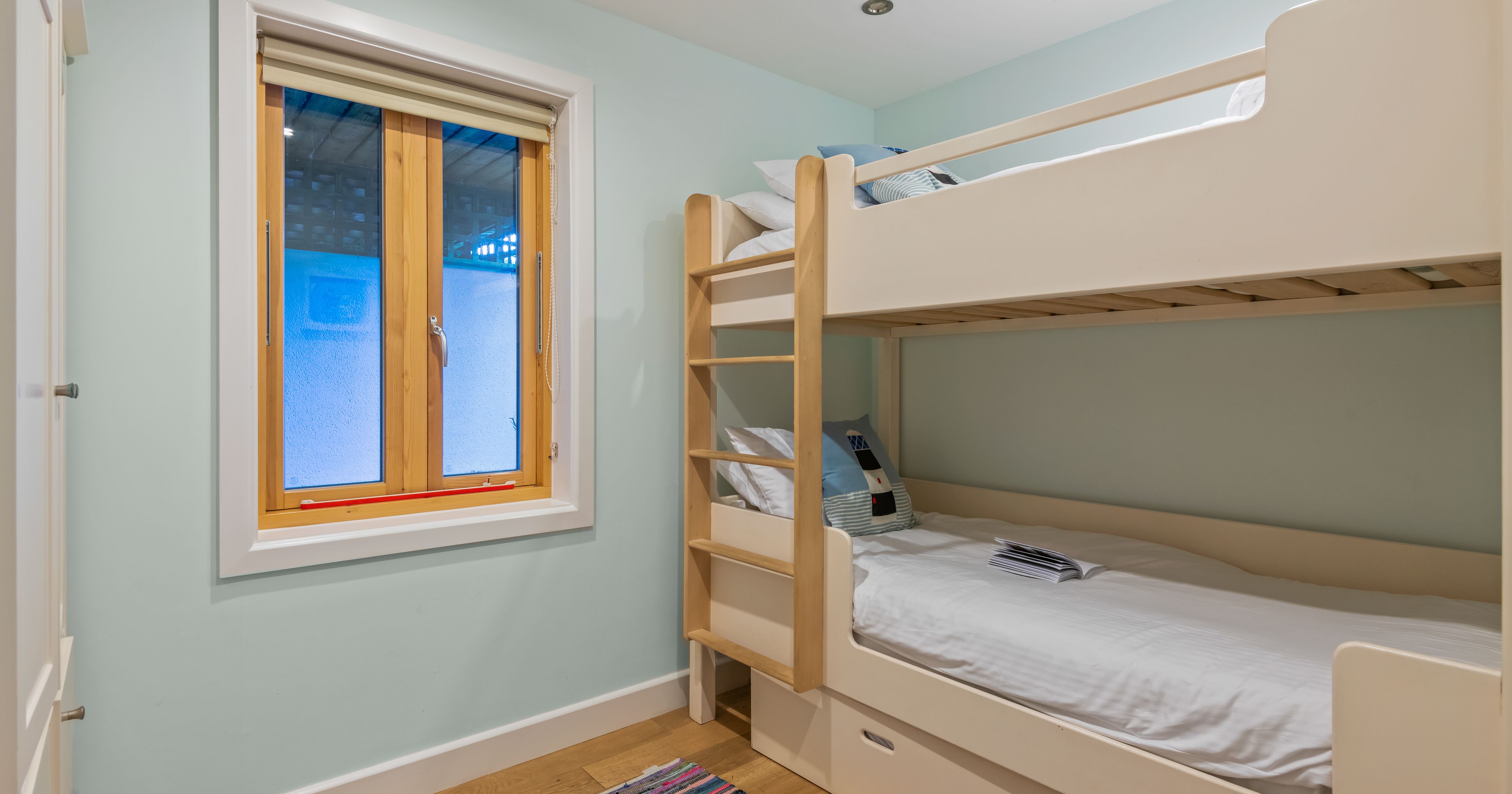 Small bedroom with light wooden bunk beds and single window