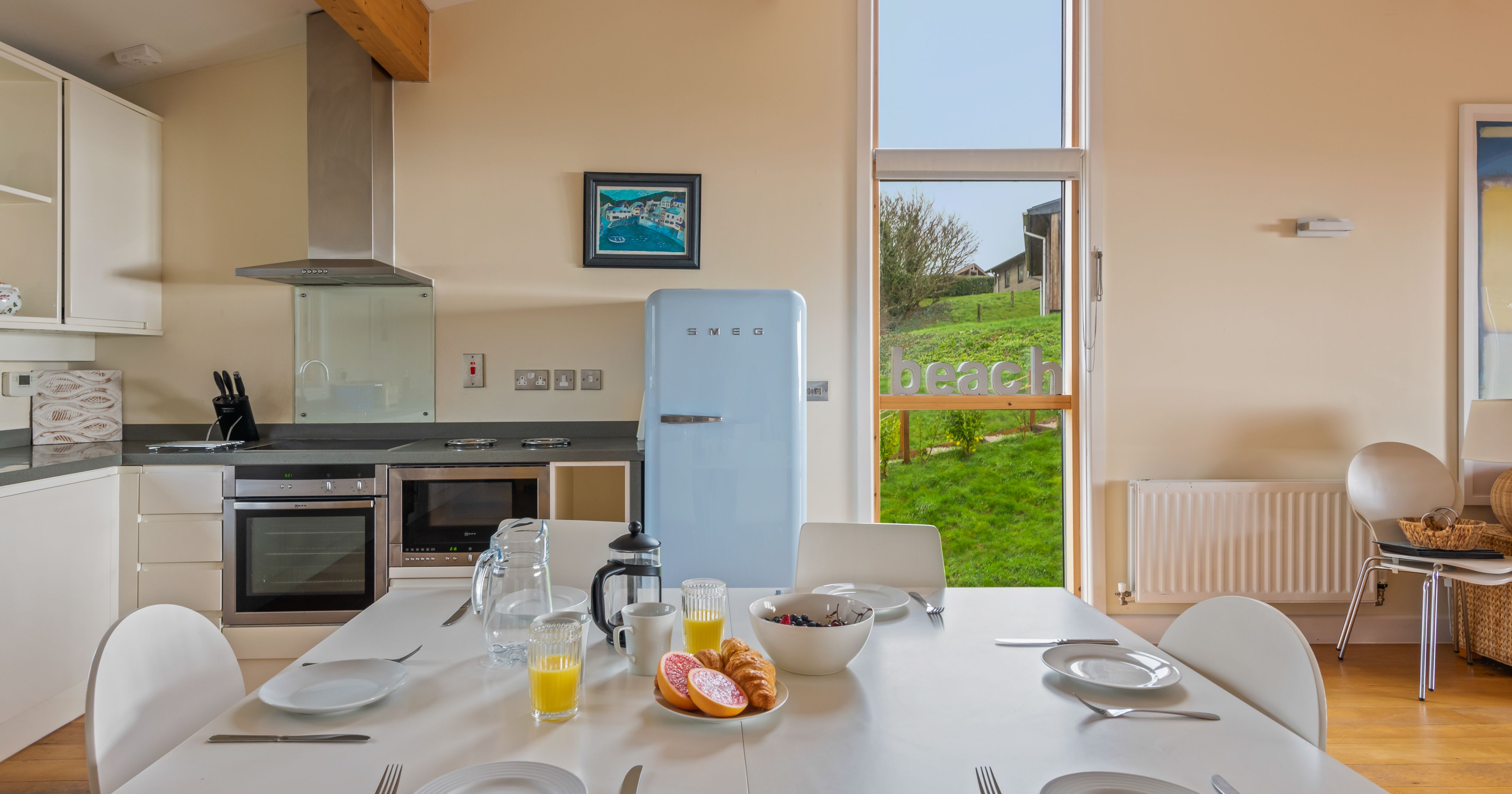 Modern kitchen and dining area with table set for breakfast and a light blue SMEG refrigerator
