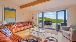 Modern living room with orange leather sofas, large windows, and outdoor hot tub