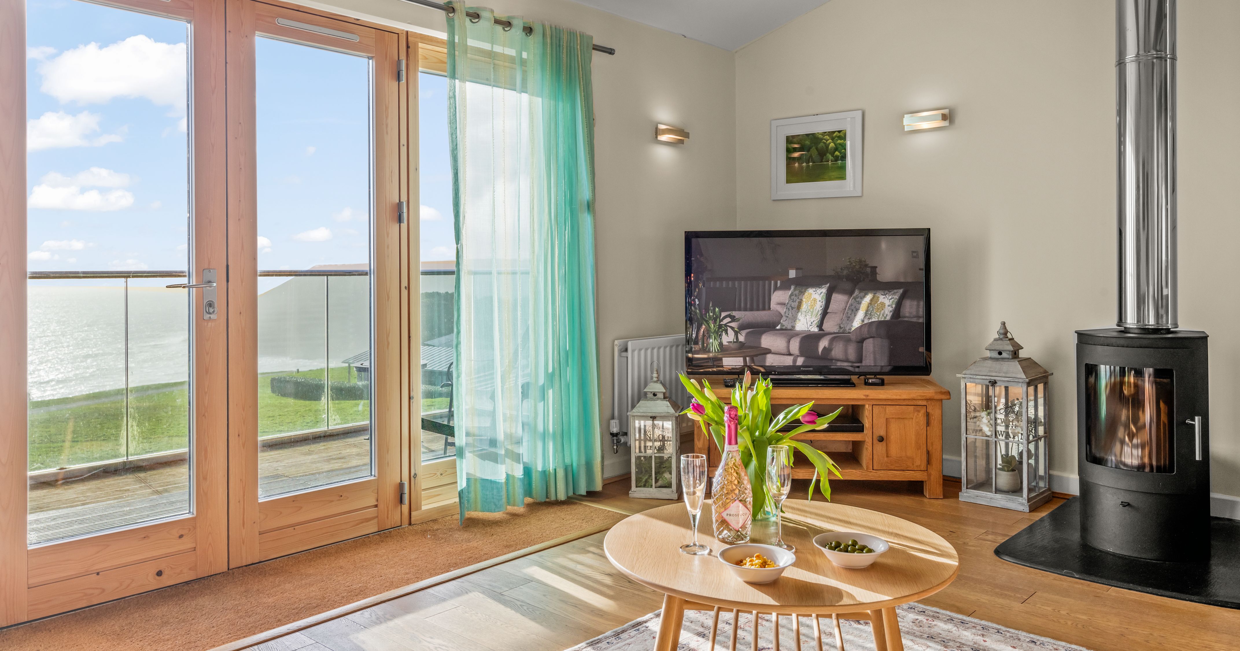 Bright living room with large glass doors, wood-burning stove, and sea view