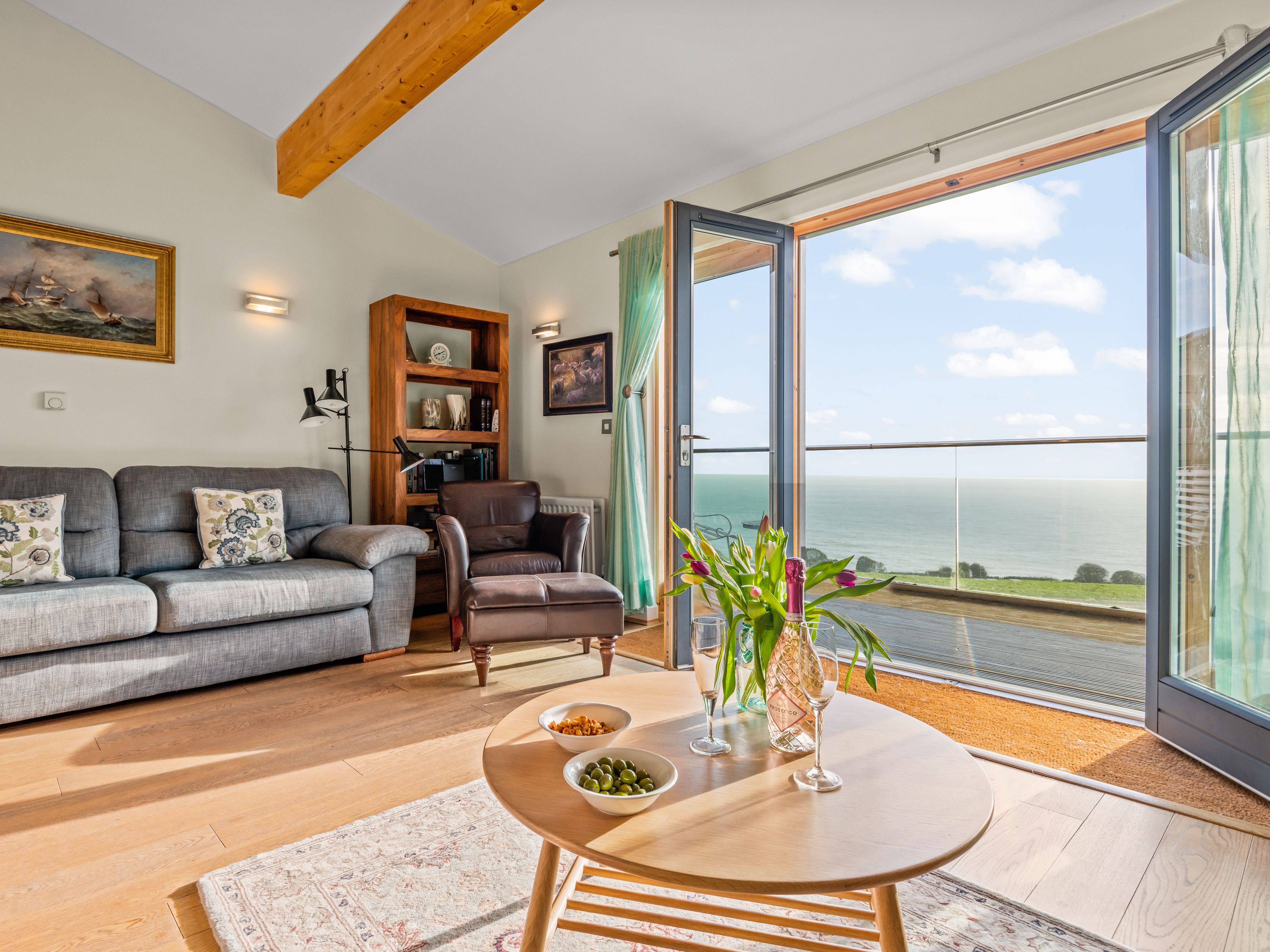 Cozy living room with sea view through open glass doors