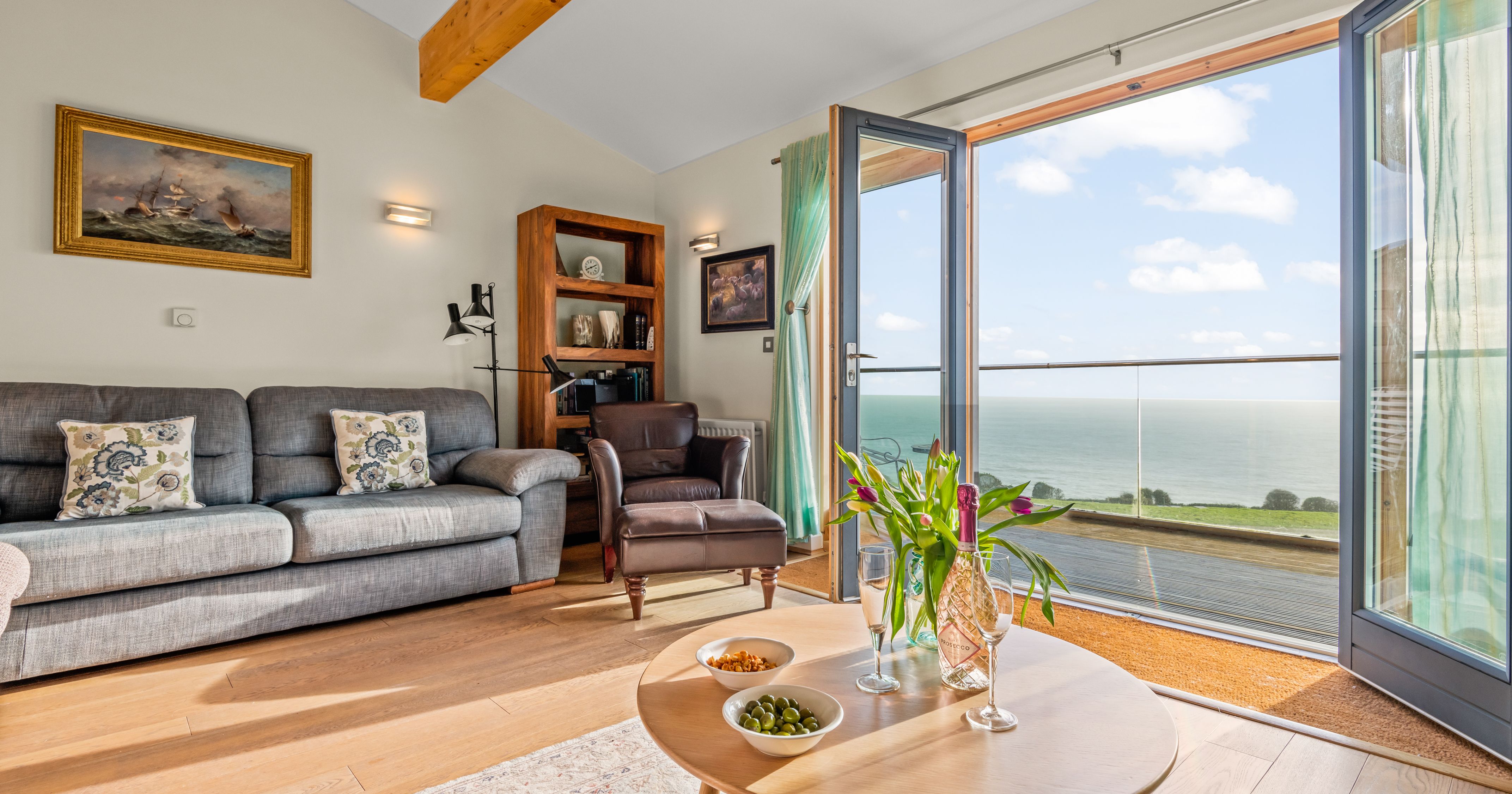 Cozy living room with sea view through open glass doors